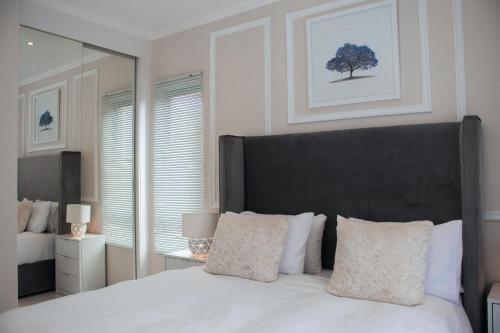 a bedroom with a large white bed with a black headboard at Luxury Sunset Gem with Power Backup in Sandton