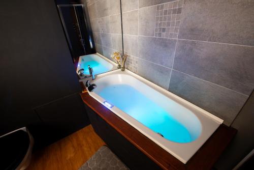 a bath tub with blue water in a bathroom at Suite Lyséa - Balnéothérapie au Coeur d'Annecy in Annecy
