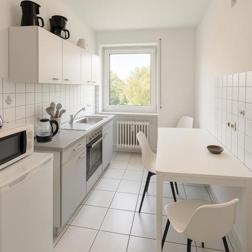 a white kitchen with a white table and chairs at Pulheim Living 6 in Pulheim