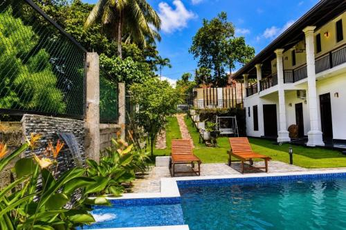 a swimming pool with chairs next to a house at Emerald Edge Villa in Minuwangoda