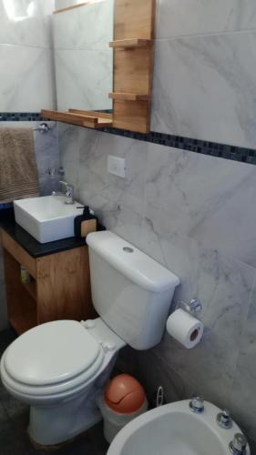 a bathroom with a white toilet and a sink at Alma in Pinamar