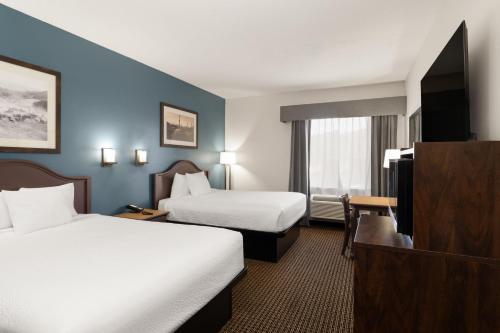 a hotel room with two beds and a flat screen tv at Tombstone Grand Hotel, a Baymont by Wyndham in Tombstone