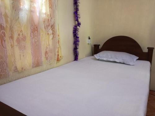 a bedroom with a bed with white sheets at Pinthu Home Stay in Sigiriya
