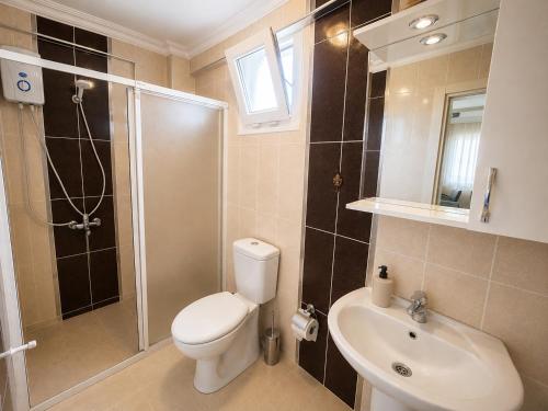 a bathroom with a toilet and a shower and a sink at Limon Pansiyon Burhaniye in Burhaniye