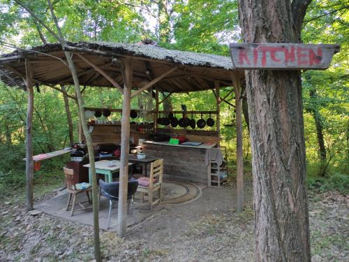 a gazebo with a table and a sign on a tree at Different Belgrade camping in Vrčin