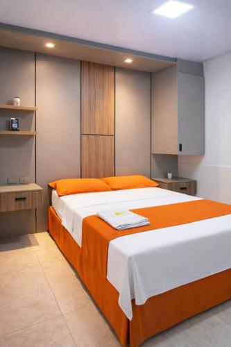 a bedroom with a large bed with orange and white sheets at Hotel Madrigal in Portoviejo