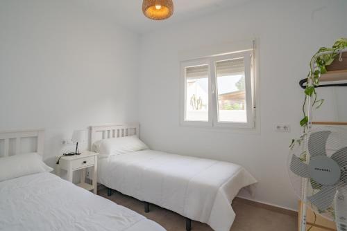 two beds in a white room with a window at La Tertulia in Zahora
