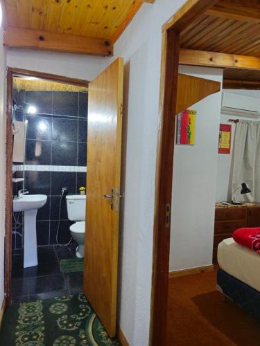 a bathroom with a sink and a toilet and a door at Raíces Cataratas in Puerto Iguazú