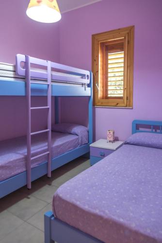 a bedroom with two bunk beds and a window at Villa Tommi a due passi dal mare in Fontane Bianche