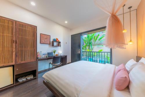 a bedroom with a bed and a desk and a window at The Coastal Haven pool villa in Hoi An