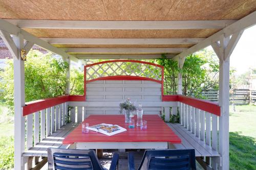 a red table and chairs on a white pergola at Villa FarbenFroh in Fehmarn