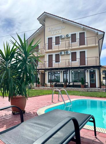 a hotel with a swimming pool in front of a building at Pensiunea Tirol Baile Felix in Baile Felix