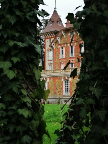 a large brick building with a tower on top of a field at Villa du Sauzin in Cronat