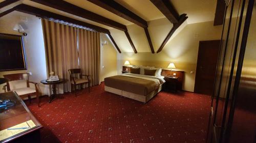 a hotel room with a bed and a table and chairs at GARDEN Club - Hotel & Restaurant - FREE Outdoor Pool & Parking in Braşov