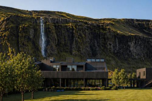 a house on the side of a mountain with a waterfall at Seljalandsfoss Horizons in Hvolsvöllur