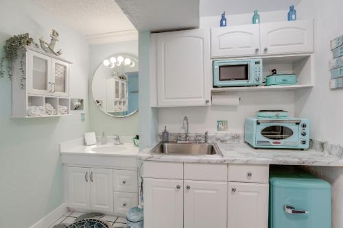a kitchen with white cabinets and a sink and a microwave at Daytona Beach Studio w/ Ocean View + Amenities! in Daytona Beach