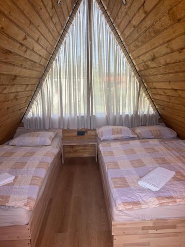 two beds in a room with a window at Hostel Ociski Raj in Kozina
