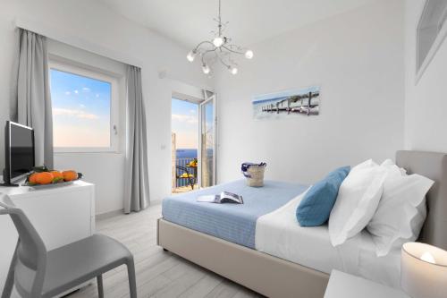 a white bedroom with a bed and a desk and a window at Amore Rentals - Villa Anna in Positano