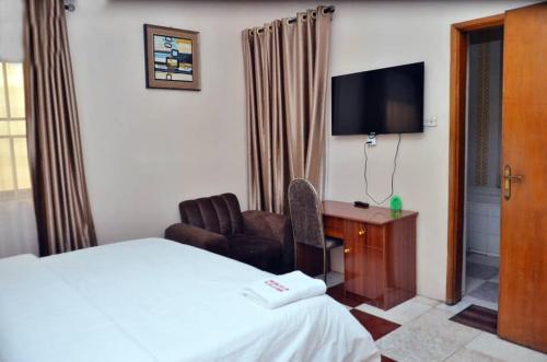 a hotel room with a bed and a chair and a television at Peace Vil in Kuto