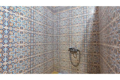 a shower stall with a patterned wall at Maison Zouala in Zouala