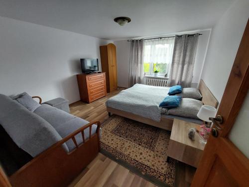 a bedroom with a bed and a couch and a window at Relaks XXL in Kartuzy