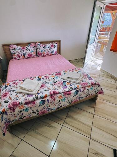 a bed with a pink comforter on a wooden floor at Casa Denisa in Sulina
