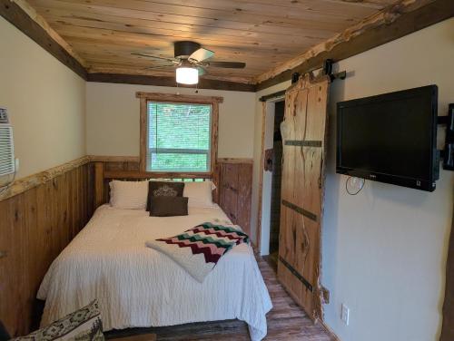 a bedroom with a bed and a flat screen tv at Lazy Bull Cottages in Bull Shoals