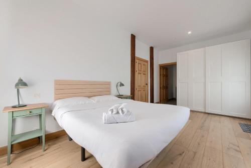 a bedroom with a large white bed and a table at Casa Eleizpe by Next Stop Bilbao in Ergoyen