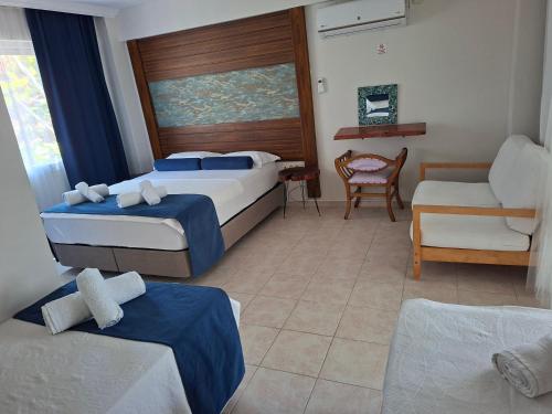 a hotel room with two beds and a chair at Hotel Antonio in Çeşme