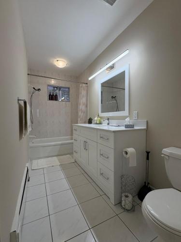 a white bathroom with a sink and a toilet at Spacious Cottage Style Home in Toronto