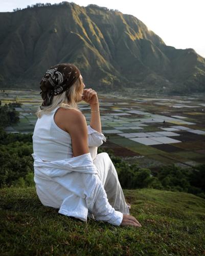 a woman sitting on a hill looking at a valley at Greentea Hostel in Labuhanhaji
