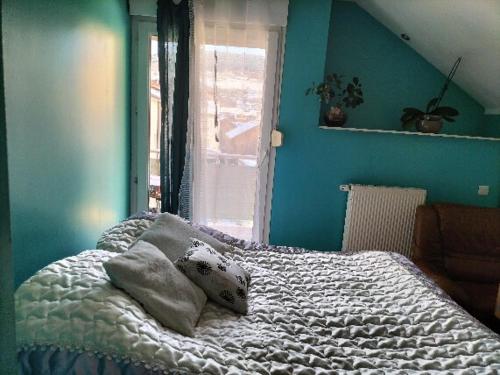 a bedroom with a bed with blue walls and a window at chambre double in Gérardmer