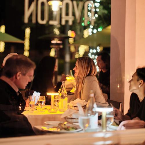 a group of people sitting at a table in a restaurant at Avalon Hotel in Miami Beach
