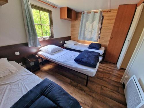a small room with two beds and a window at Camping Paus'Art Déco in Villemer