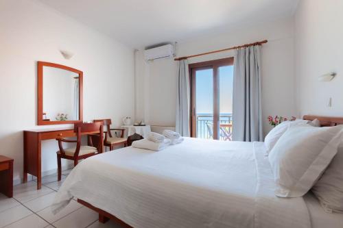 une chambre blanche avec un lit, un bureau et une fenêtre dans l'établissement Pramataris, à Monemvasia