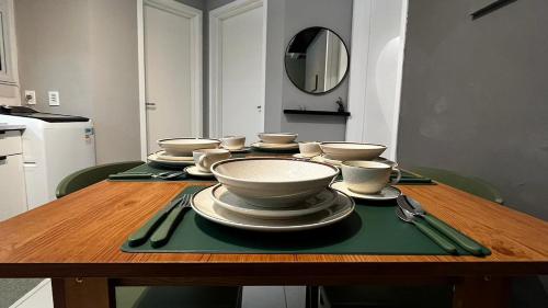 a wooden table with bowls and plates on it at Apartamento Moderno em Floripa - Ideal para Famílias in São José