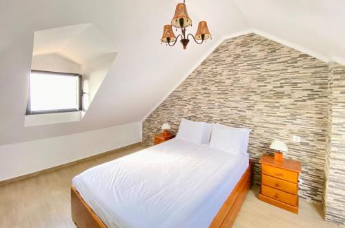 a bedroom with a large bed and a brick wall at O Cantinho do Pargo in Ponta do Pargo