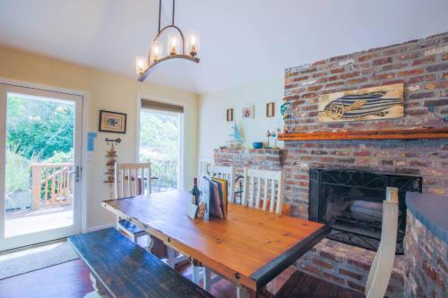 a dining room with a brick fireplace and a wooden table at Shell Station House in Folly Beach