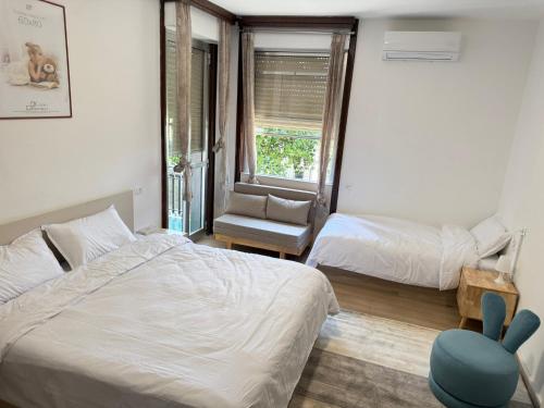 a bedroom with two beds and a chair and a window at Happy Hue rooms Malpensa airport in Samarate