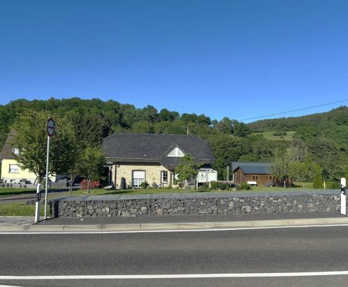 a house with a stone wall next to a street at Appartment Haus Müller in Kelberg