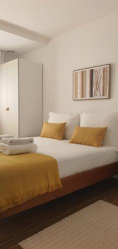a bedroom with a large white bed with yellow pillows at Casa de Salgueiros in Canidelo