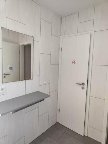 a white bathroom with a door and a mirror at Kleine Auszeit in Schermbeck