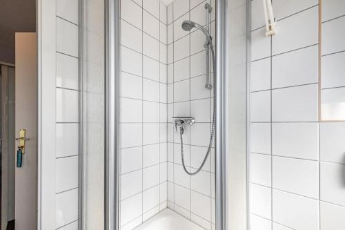 a shower in a bathroom with white tiles at Sonne in Diedrichshagen