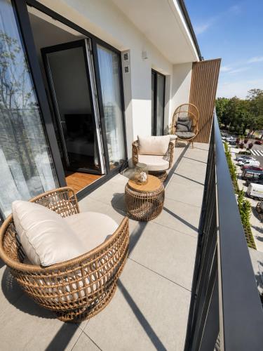 a balcony with wicker chairs and tables on a building at Essentia Apartament 405 in Dziwnów