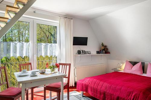 a bedroom with a red bed and a table and chairs at Sonne in Diedrichshagen