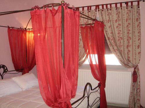 - une chambre avec des rideaux rouges et un lit avec une fenêtre dans l'établissement Les Caselles de Marie, à Aumelas