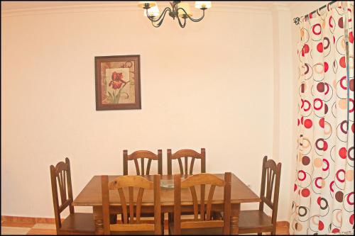 a dining room with a wooden table and chairs at Apartamento San José Conil in Conil de la Frontera