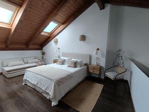 ein weißes Schlafzimmer mit einem Bett und einer Couch in der Unterkunft Aneto Dúplex en Badaguas in Badaguás