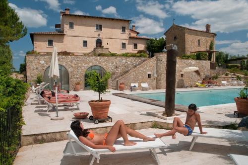 two women laying on lounge chairs in front of a house at Tenuta Decimo - Villa Dini in San Gimignano