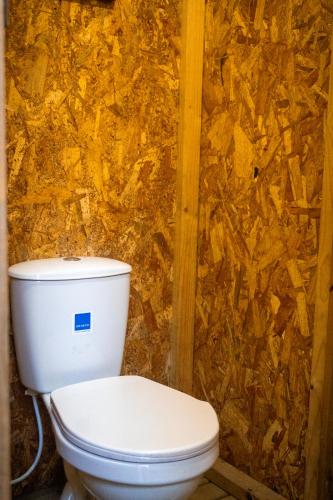 a bathroom with a toilet in front of a wall at Refugio Munay in Florián